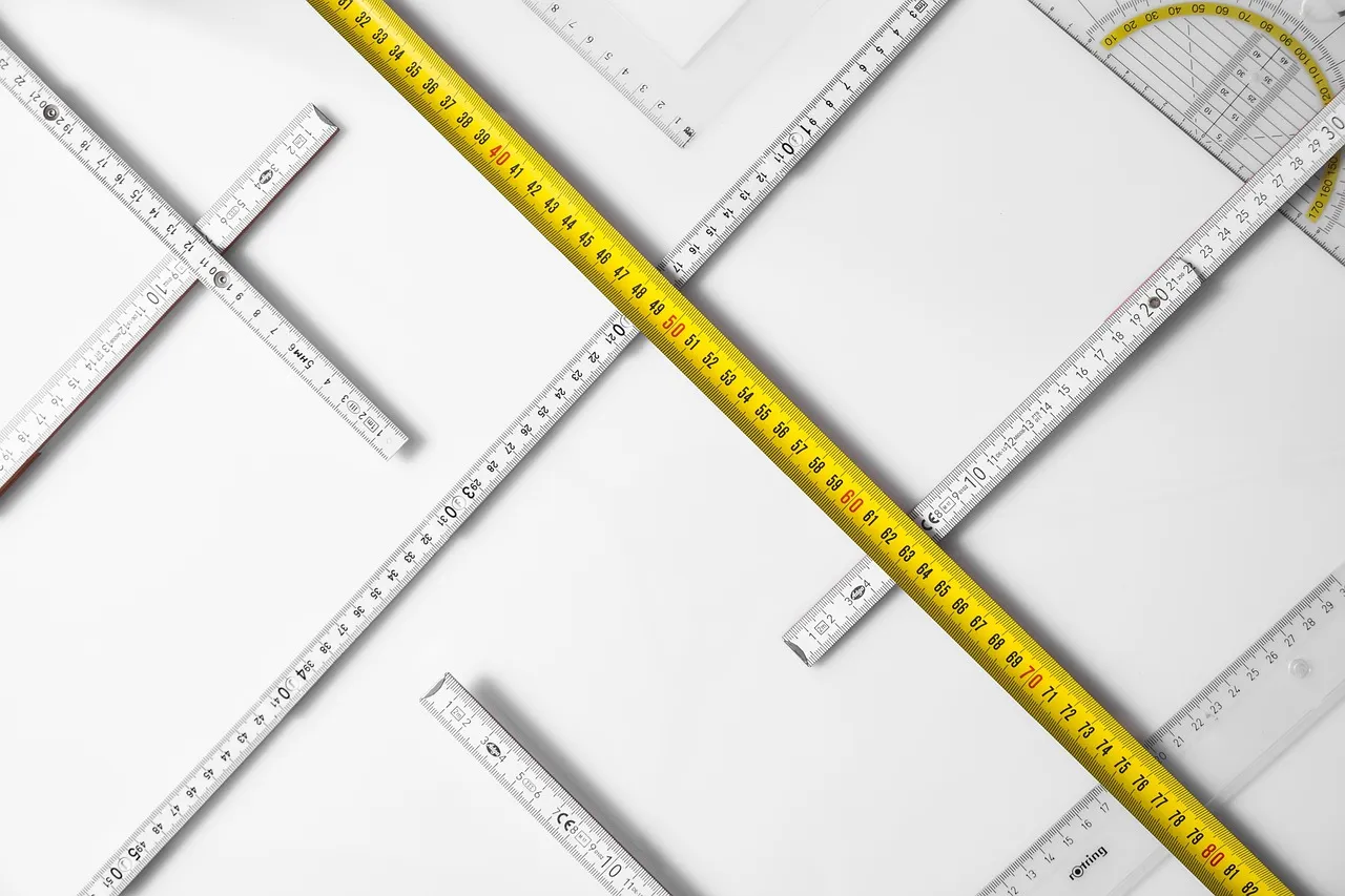 Various measuring tools on a white surface, including folding rulers and a protractor.