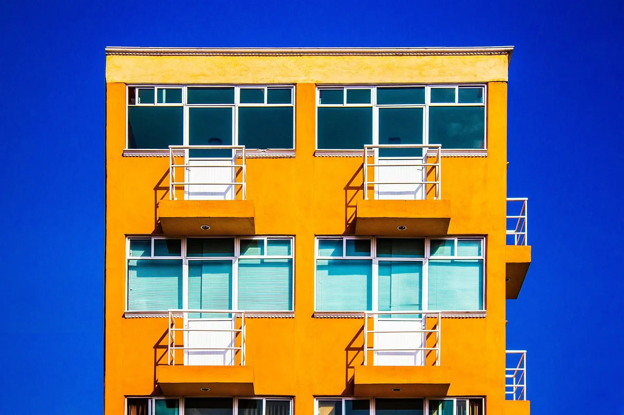 Orange residential building with small balconies against a bright blue sky.