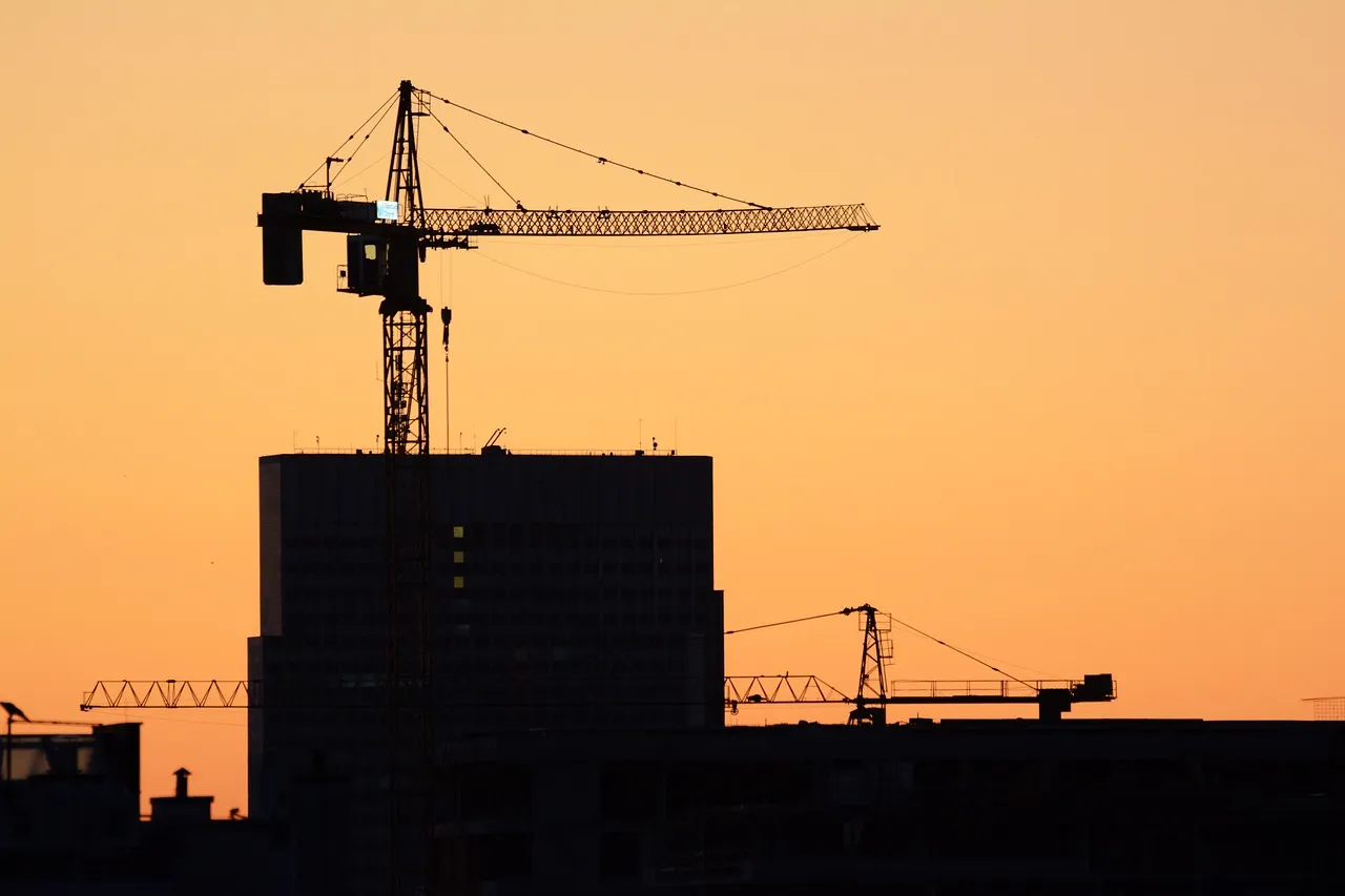 Construction cranes silhouetted against an orange sky, showcasing civil earthwork and reinstatement projects.