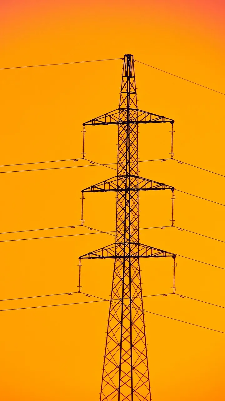 Power line tower against a vibrant orange sky