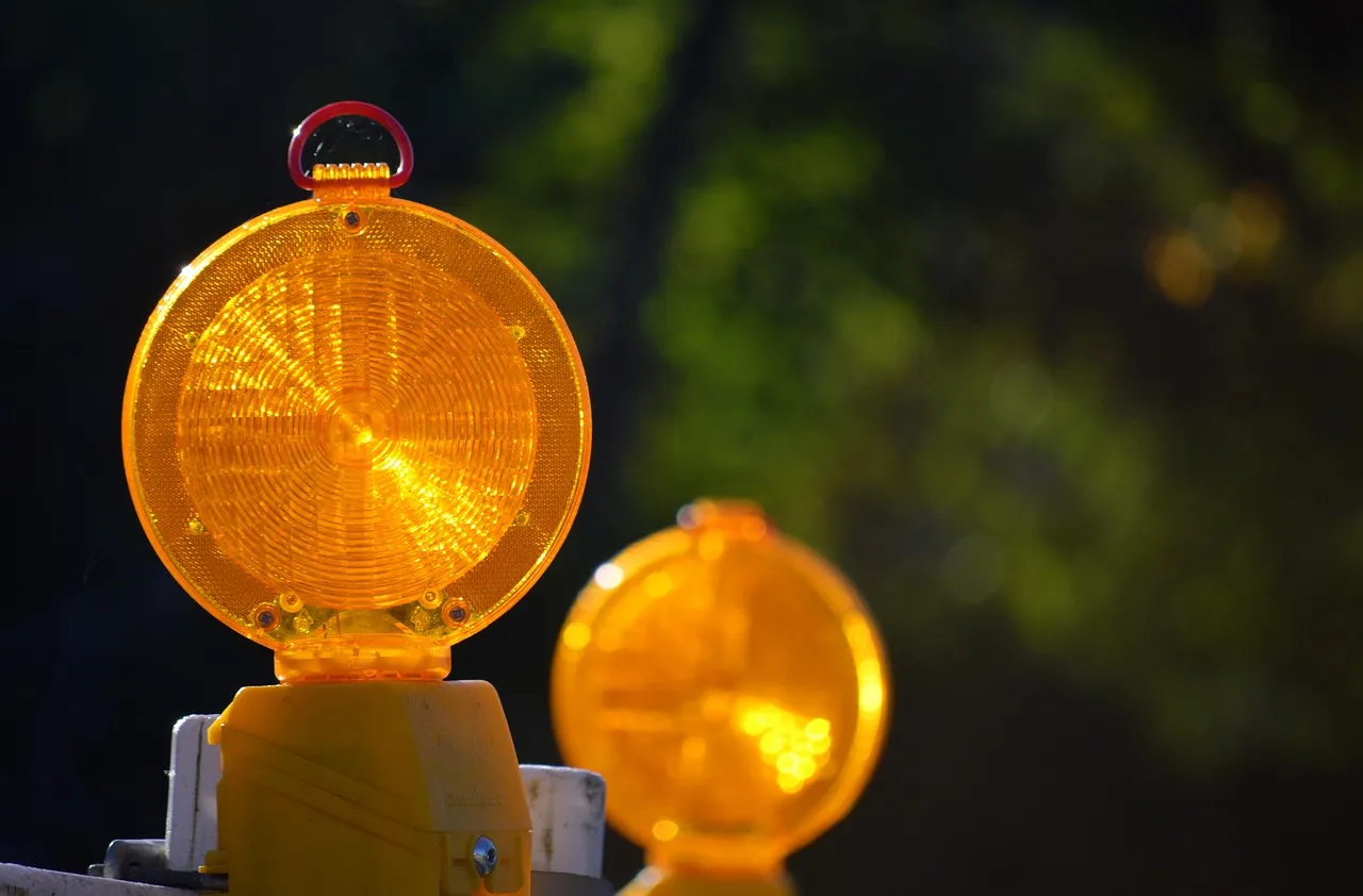 Two flashing yellow construction lights, warning of road work ahead.
