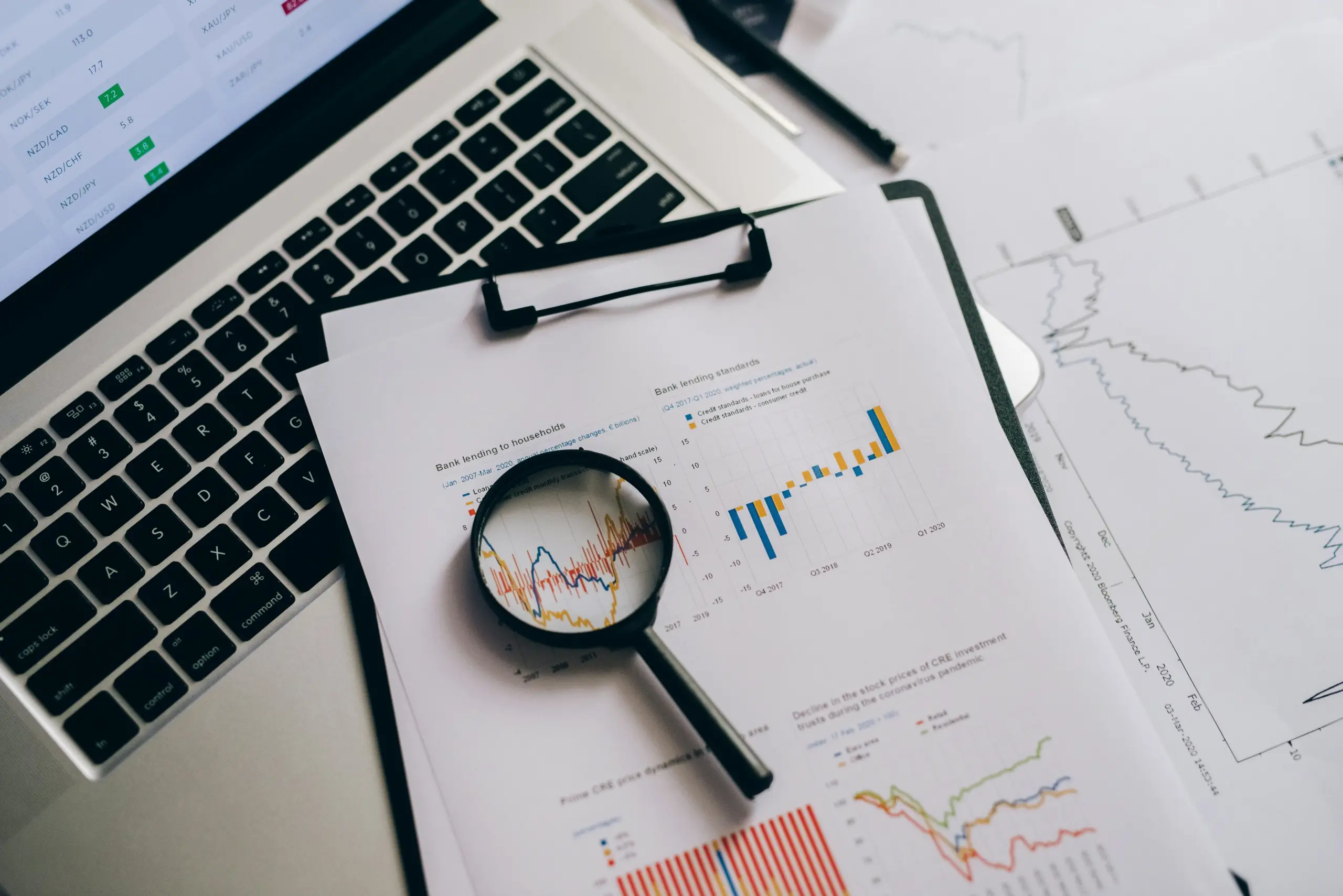 Financial analysis: charts, graphs, and laptop showing bank lending trends. Bloomberg Finance copyright visible.