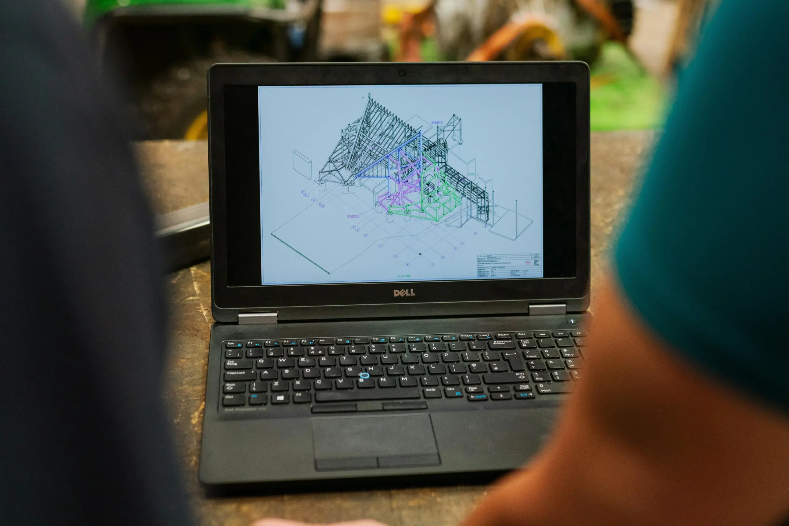 Laptop displaying a 6D BIM model, likely for operation and maintenance, with people viewing the design.