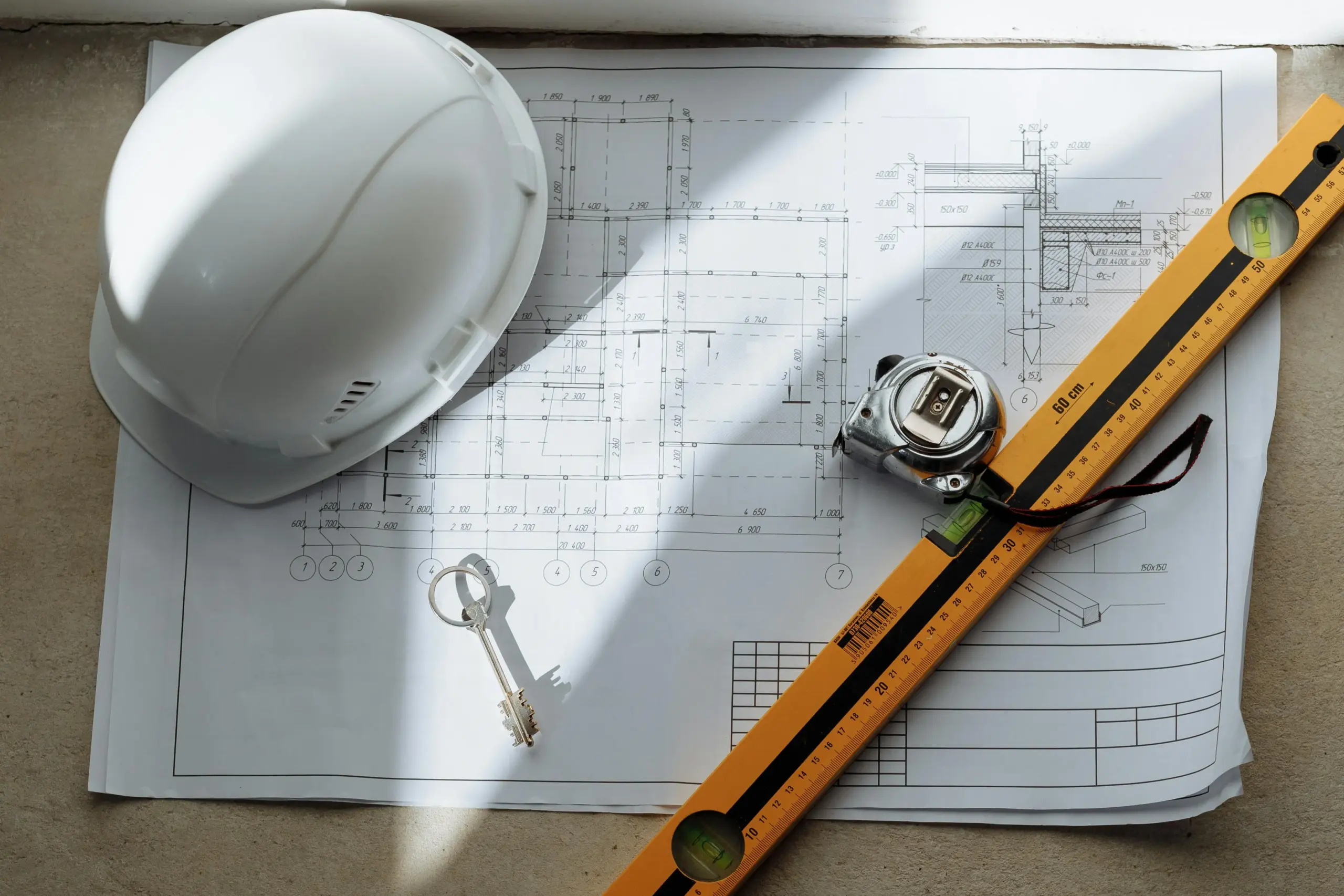 Construction blueprint with hard hat, tape measure, level, and keys. 6D BIM Operation & Maintenance model.