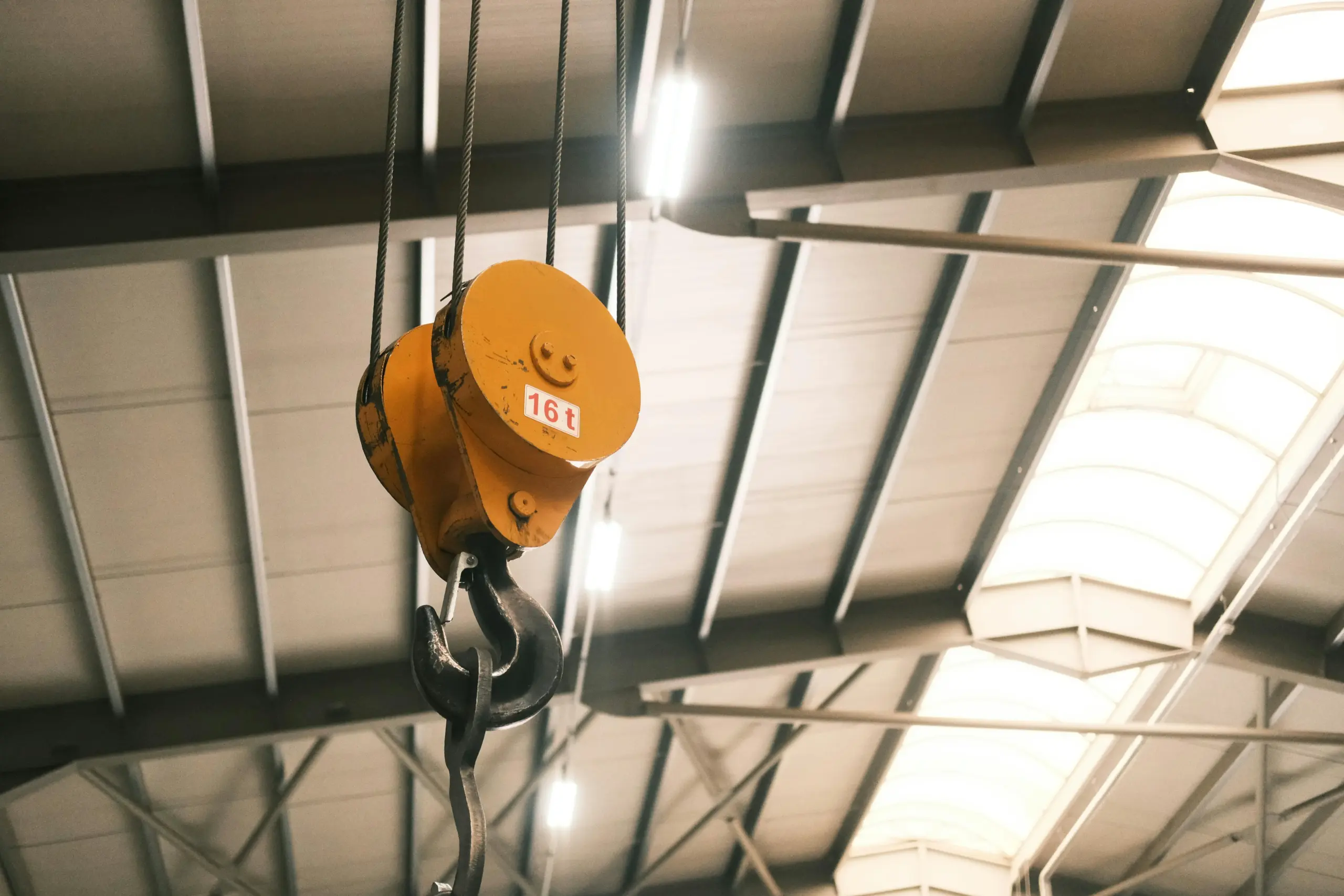 Industrial crane hook with a 16-ton capacity in a factory setting.